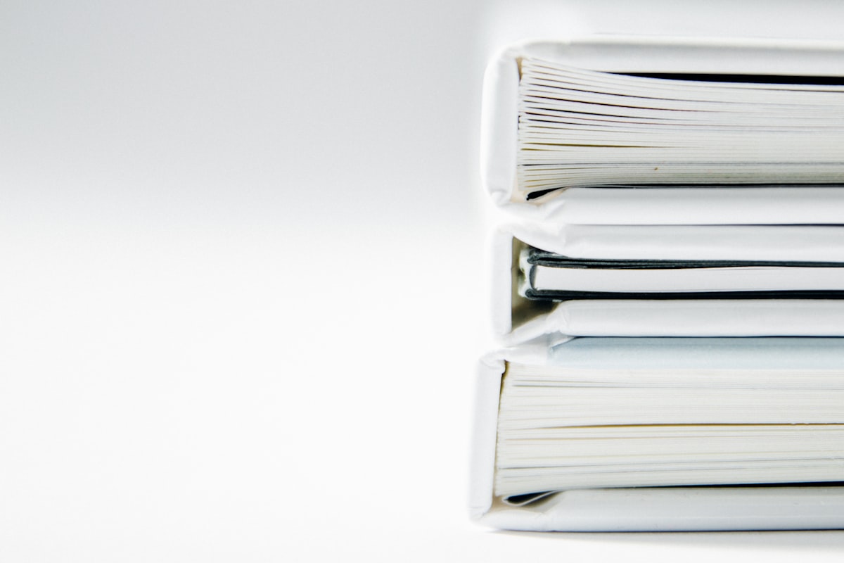 A stack of thick, well-worn document folders on a white surface, representing the unstructured paperwork FloHoard turns into governed digital assets