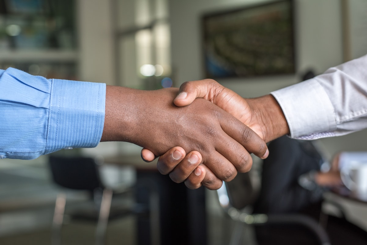 Two business partners shaking hands across a meeting table after signing an agreement