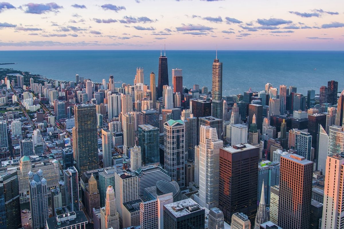 An aerial view of a dense city financial district at dusk beside the water, representing the telecom, banking, and insurance enterprises deploying Decision Intelligence